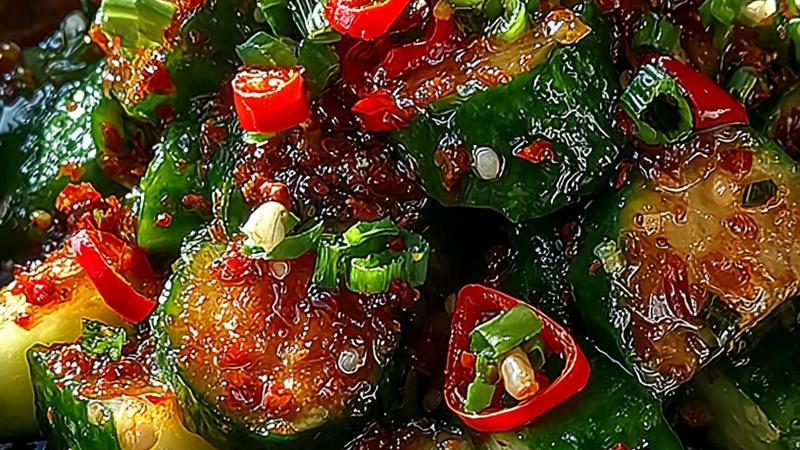 Overhead view of vibrant smashed chili crisp cucumber salad with crispy garlic and chili flakes, fresh green onions, and sesame seeds scattered across rustic wooden serving bowl